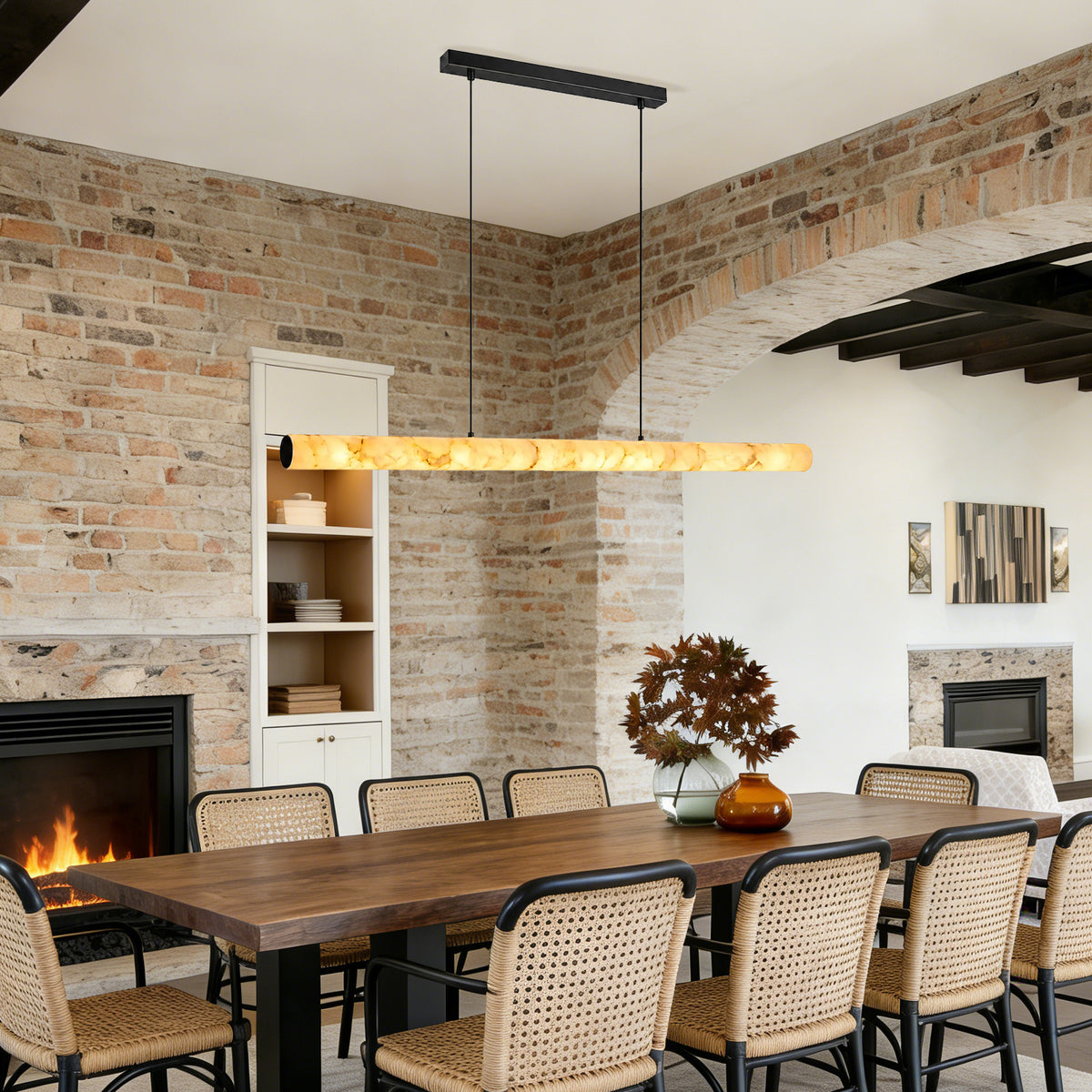 Linear alabaster pendant light suspended above a long wood dining table in a rustic dining room