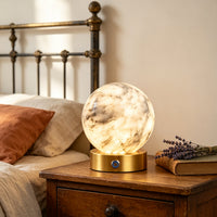Glowing alabaster globe table lamp beside a bed